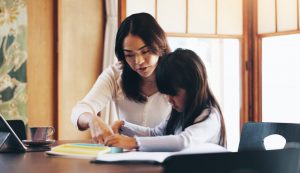 A mother teaching her daughter at home.