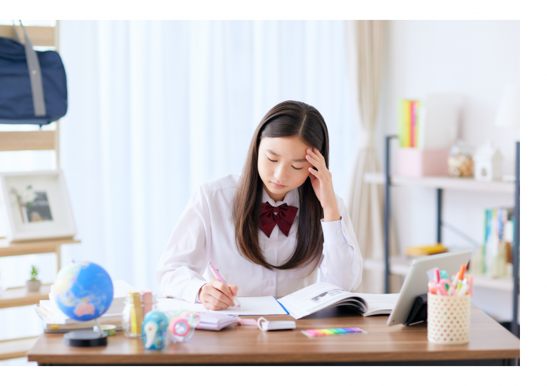 A girl looks stressed while studying with hand on her head.