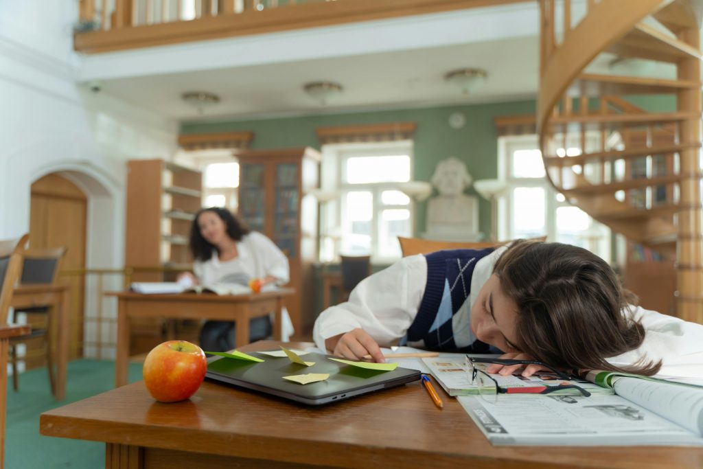 A girl with her head on the table, stressed about studying.