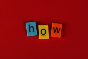 The word "how" spelled out with blue, yellow, and orange letter tiles
