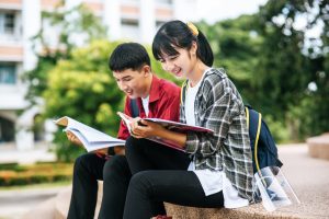 Male and female students sitting and reading books on the stairs