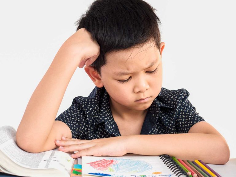 Young boy looking frustrated with hand on head while doing homework
