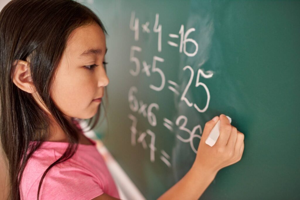 Girl solving Maths problems on the chalkboard