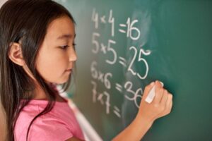 Girl solving Maths problems on the chalkboard
