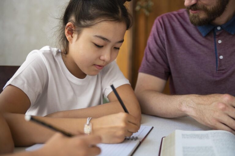 Student taking notes while studying with an adult