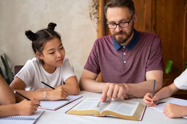 Male teacher with glasses teaching children during group study session