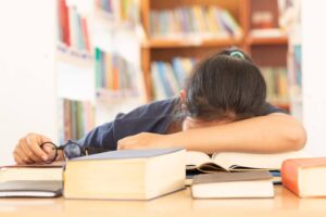 Student feeling stressed while studying with books on a desk