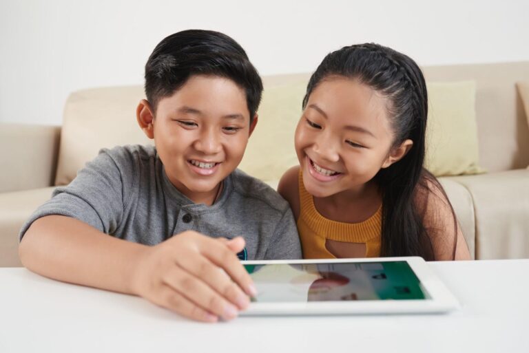 Two children using a tablet together at home for learning and play